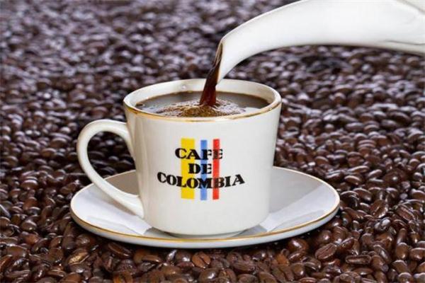 Tradicinė Kolumbietiška kava pilama į puodelį, apsupta tūkstančiais kavos pupelių